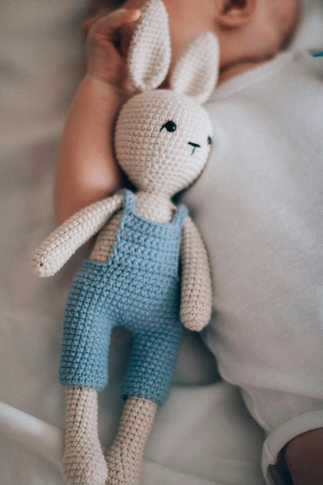 A handmade crochet amigurumi bunny in blue dungarees